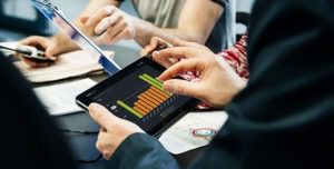 CLoseup of an employee looking at a graph on his tablet with his team