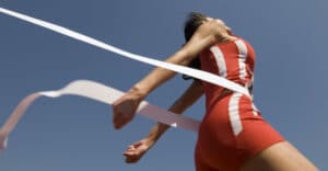 A young female athlete in red jersey crossing the finish line by